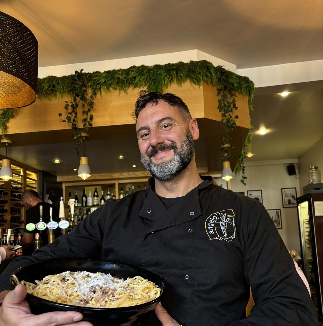 Chef Federico Trulli, the owner of Angelo’s Ristorante in Sunderland, smiling and presenting a bowl of fresh, authentic Italian carbonara.